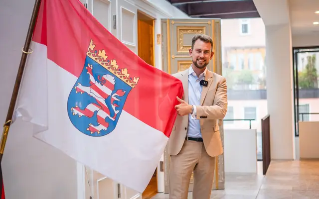 Maximilian Bathon vor der hessischen Landesflagge
